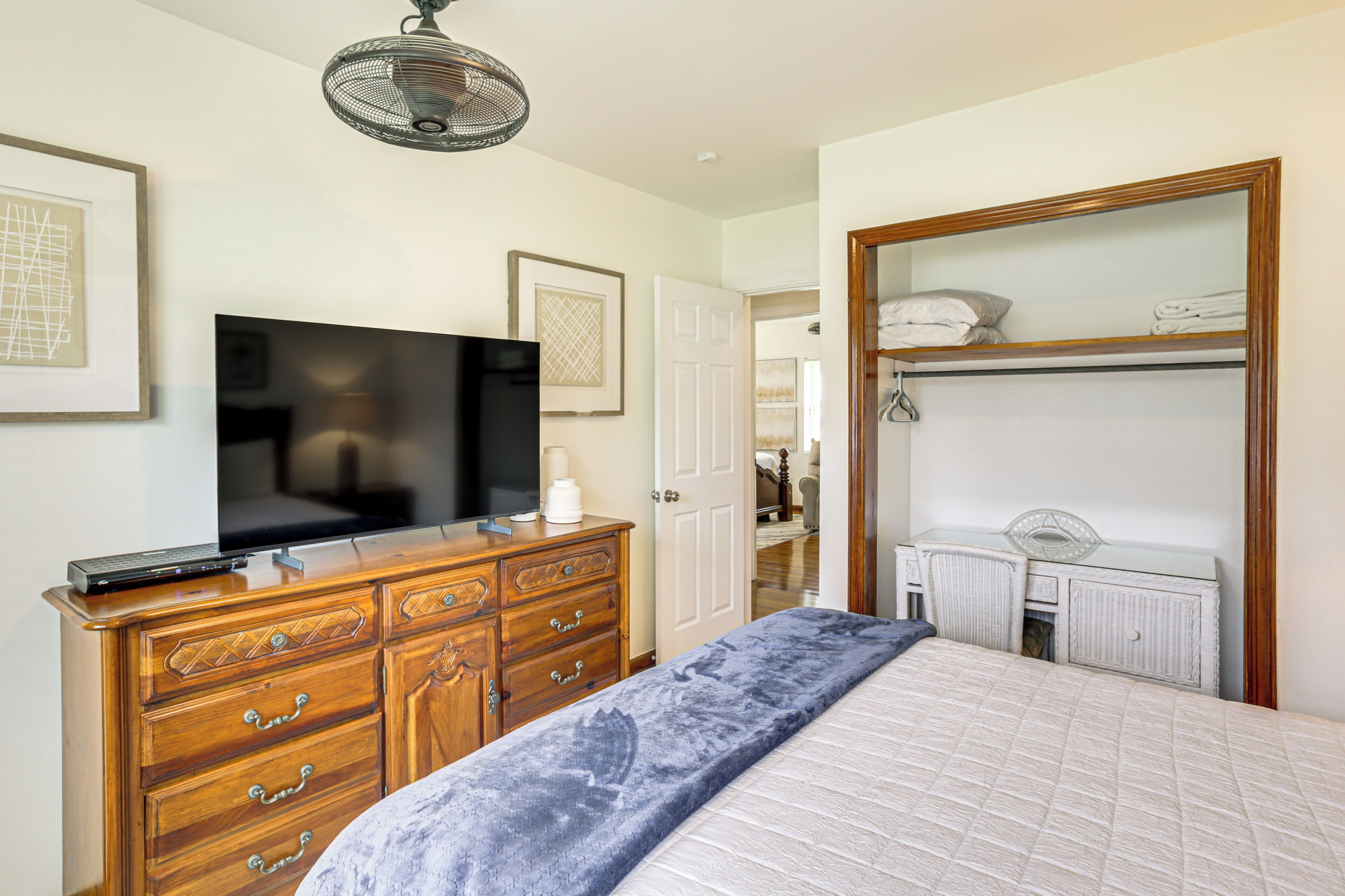 Un dormitorio con cama, cómoda, televisor y vestidor.