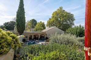 Un bâtiment en pierre doté d’une piscine, entouré d’une végétation luxuriante et de grands arbres.