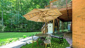 A patio with a table and chairs, an umbrella, and a brick wall.