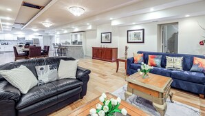 A spacious living area with a black leather sofa, a blue sofa, and a wooden coffee table with a vase of flowers.