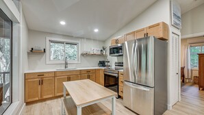 A modern kitchen with wooden cabinets, stainless steel appliances, a window, and a view of trees. - Screened Porch w/ Lake View! Tolland Family Haven (Granville)