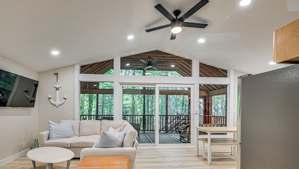 A spacious living area with a high ceiling, a ceiling fan, and a large sliding glass door leading to a deck. - Screened Porch w/ Lake View! Tolland Family Haven (Granville)