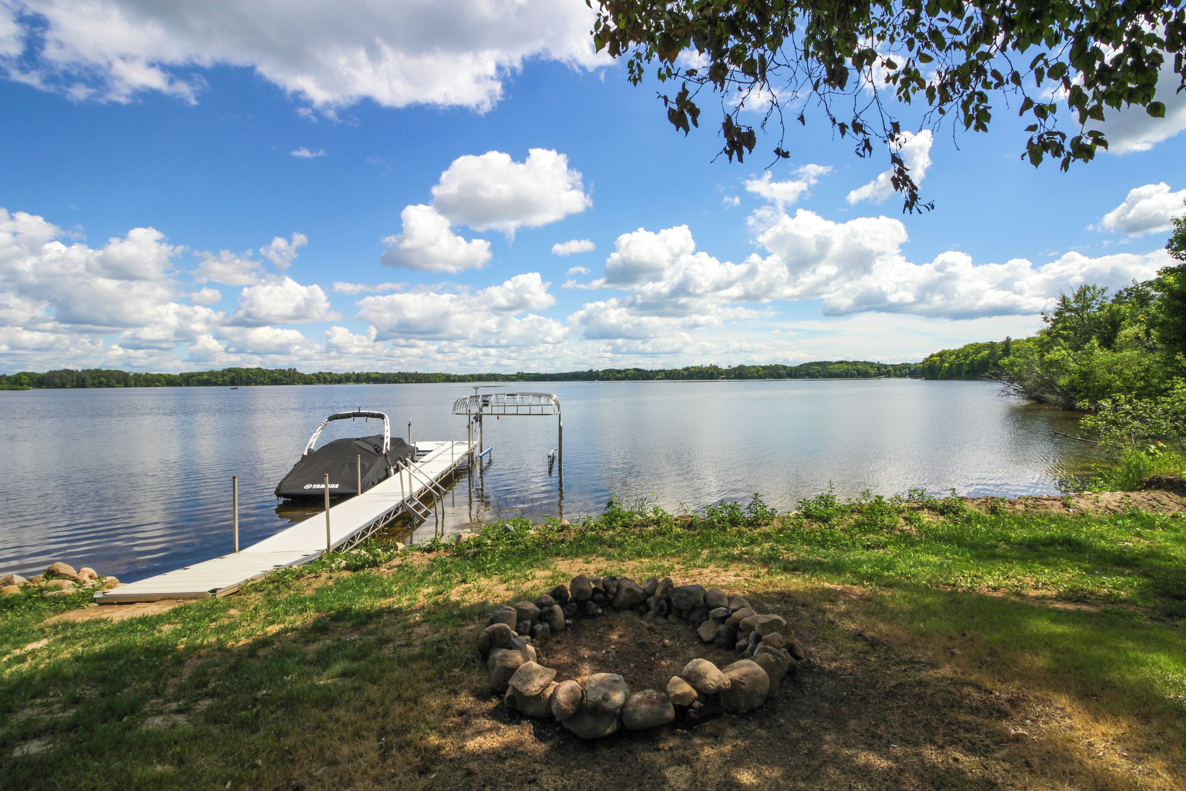 Une jetée au bord du lac avec un bateau, un foyer en pierre et un ciel dégagé.