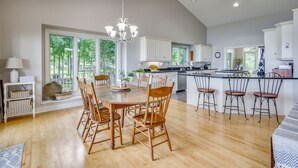 Een ruime keuken met een groot eiland, een houten eettafel en stoelen.