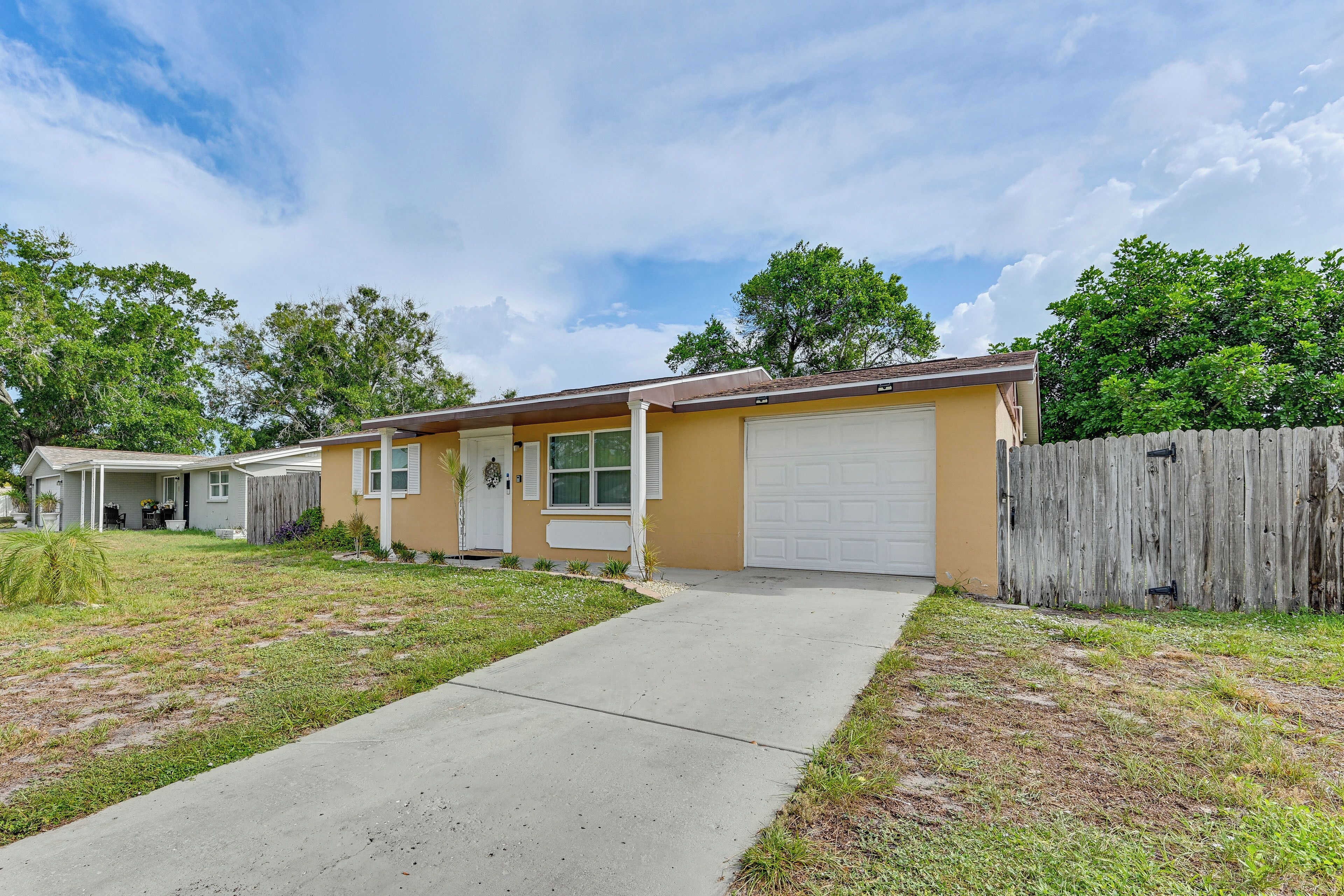 A residential house with a garage, a front yard, and a wooden fence.