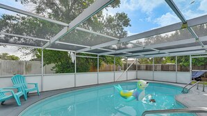 A covered swimming pool with a diving board, a small inflatable toy, and two turquoise chairs. - Private Pool! Port Richey Home Near Coast & Trails (Port Richey)