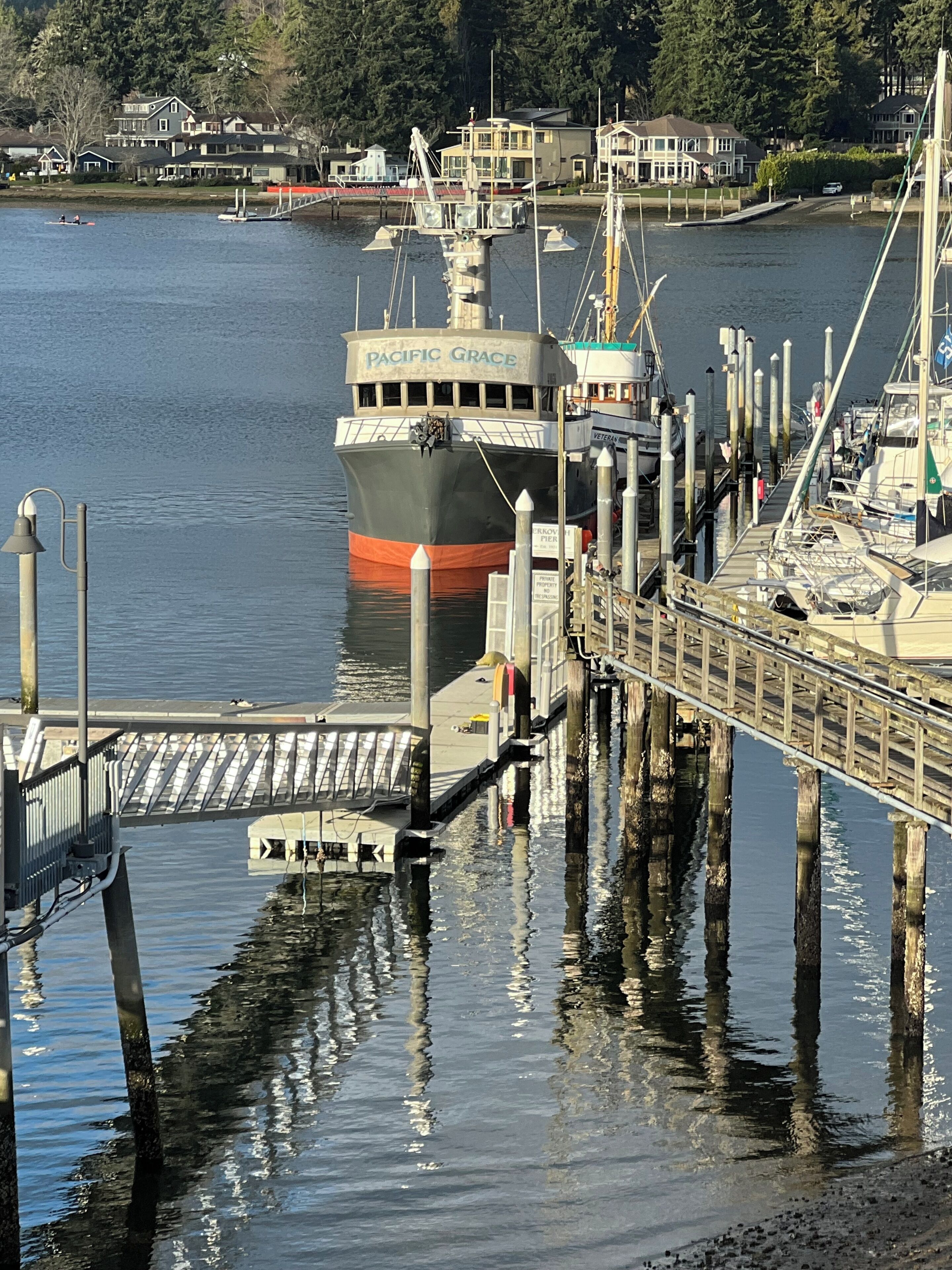 Un muelle de transbordador con un barco grande llamado 'Pacific Grace' y un espigón que se adentra en el agua.
