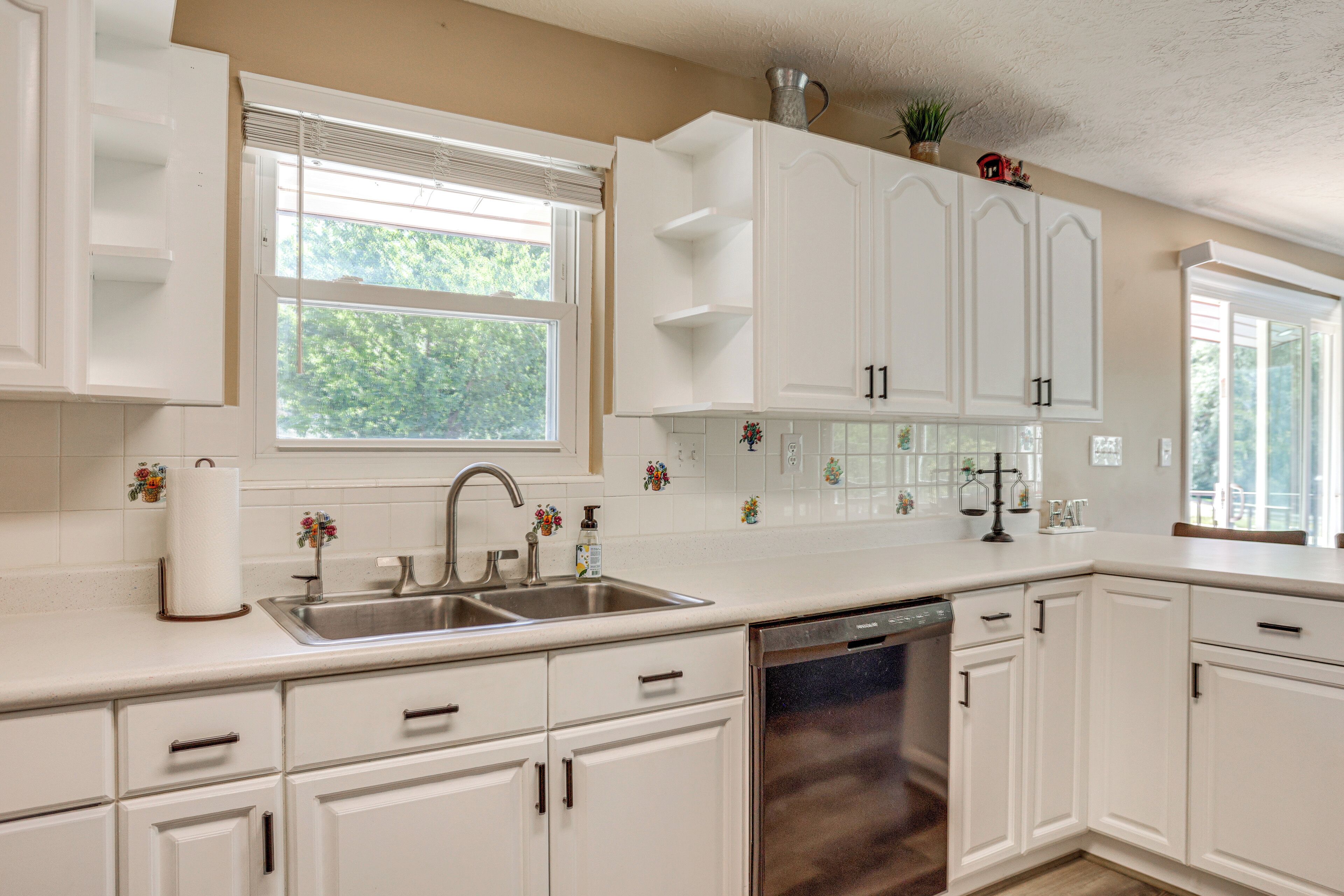 A kitchen with white cabinets, a stainless steel sink, and a dishwasher.
