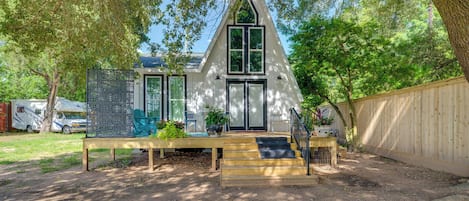 Ein Haus mit einem steilen Satteldach, einer Veranda mit Stufen und einem Holzzaun, der das Grundstück umgibt.