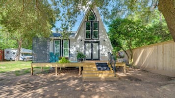 A house with a steeply pitched roof, a front porch with steps, and a wooden fence surrounding the property.