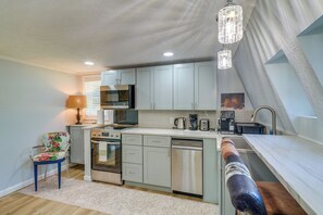 A modern kitchen with a central island, built-in appliances, and a hanging light fixture. - 3 Mi to Tomball's Main St! Unique A-frame Home (Tomball)
