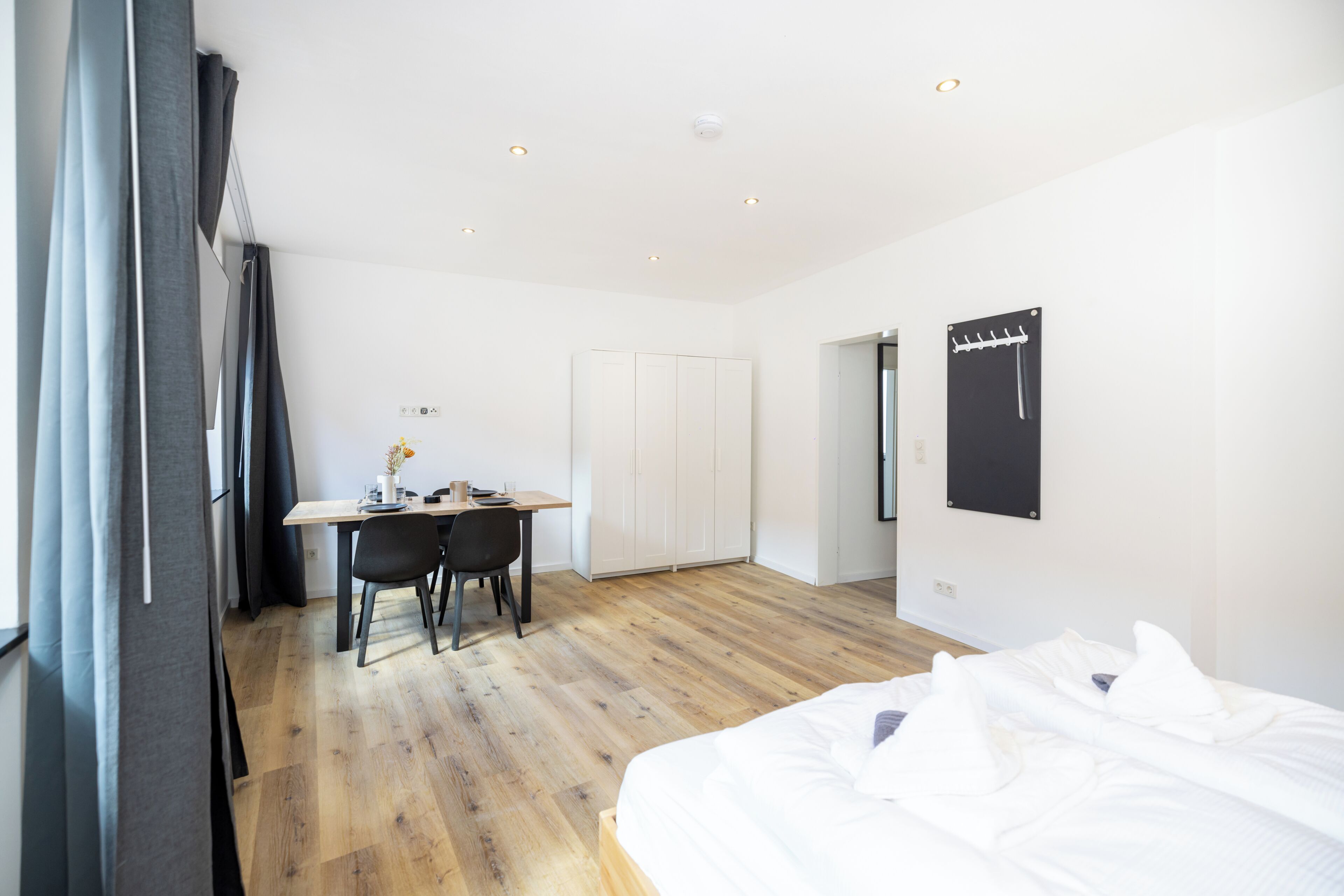 Ein modernes Schlafzimmer mit Holzboden, einem Bett, einem Schreibtisch und einem Kleiderschrank.