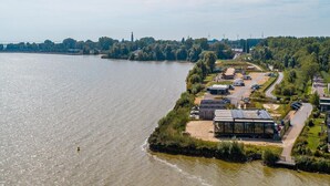 Une propriété située au bord de la rivière, dotée d’un quai, d’un petit bâtiment à la façade en verre et d’un espace de stationnement.