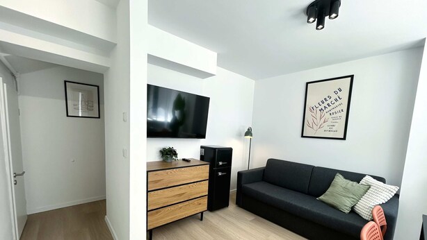A modern living room with a flat-screen TV, a dark sofa, a wooden cabinet, and a framed artwork on the wall. - Stylish Apartment in Eimsbuettel Hamburg for 4 (Hamburg)