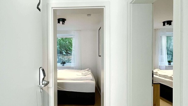 Une chambre moderne avec un lit, une fenêtre et une porte donnant sur une autre pièce.