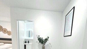 Une pièce moderne et minimaliste, avec une table à manger, des chaises, une plante en pot et un tableau encadré au mur.