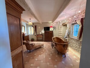Habitación con una bañera antigua, muebles de madera y una pared de piedra.