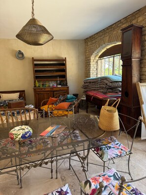 Una habitación rústica con pared de piedra, un armario de madera, una mesa de vidrio y una cesta de mimbre.