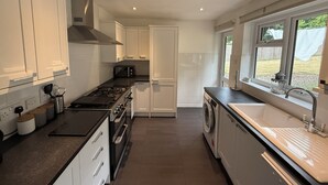 Una cucina moderna con mobili bianchi, un fornello a gas, forno integrato, lavatrice e lavandino.