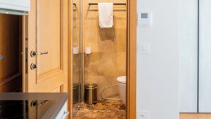 Ein Badezimmer mit Duschabtrennung aus Glas, einem Handtuch auf einem Haken, einer Toilette und einem Poster an der Wand.