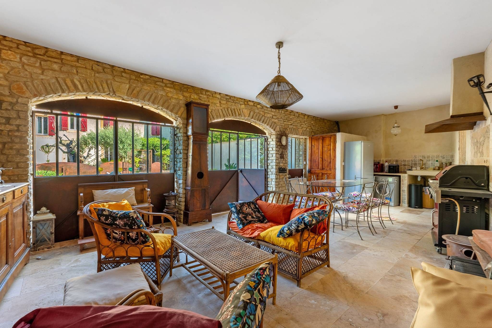 A cozy living area with wicker furniture, a stone wall, and a view through a large window.