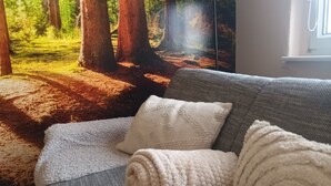 Ein Wohnzimmer mit einer Couch, einer Decke und einer Lampe.