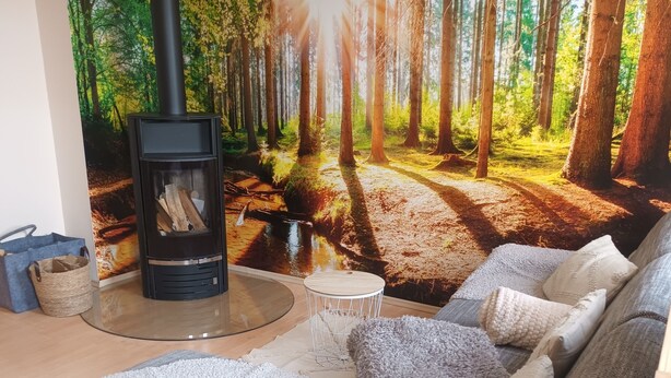 Ein gemütliches Wohnzimmer mit Kamin, einer Couch und einer Wandmalerei zum Thema Wald.