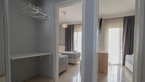 Ein Hotelzimmer mit Bett, Sitzgelegenheit mit Tisch und Stühlen, Kleiderschrank und Blick ins Freie.