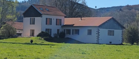 A two-story house with a red-tiled roof, a white exterior, and a sloped roof.