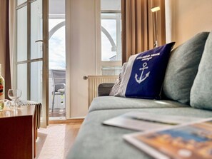 Ein Zimmer mit einer Couch, einem Tisch mit einem Glas und Blick durch eine Glastür.