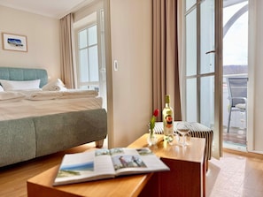 A hotel room with a bed, a table with a magazine, a bottle, and a glass. - Moderne Ferienwohnung mit Balkon in Sudostlage in Sellin (Sellin)