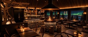 A restaurant with a stone fireplace, wooden tables, and chairs, and a view of the northern lights. - Aava Glass Igloos (Rovaniemi)