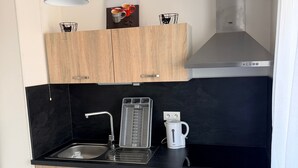 Uma cozinha moderna com armários de madeira, bancada preta, forno embutido e coifa de aço inoxidável.