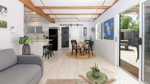 A modern interior with a dining area, kitchen, and living space. - Paperbark Cottage - New Tropical Holiday Rental (Port Douglas)