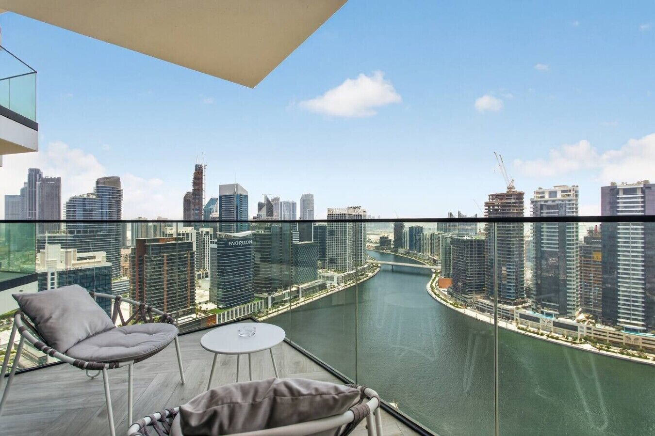 Un balcone con ringhiera in vetro che si affaccia su una città e un fiume.
