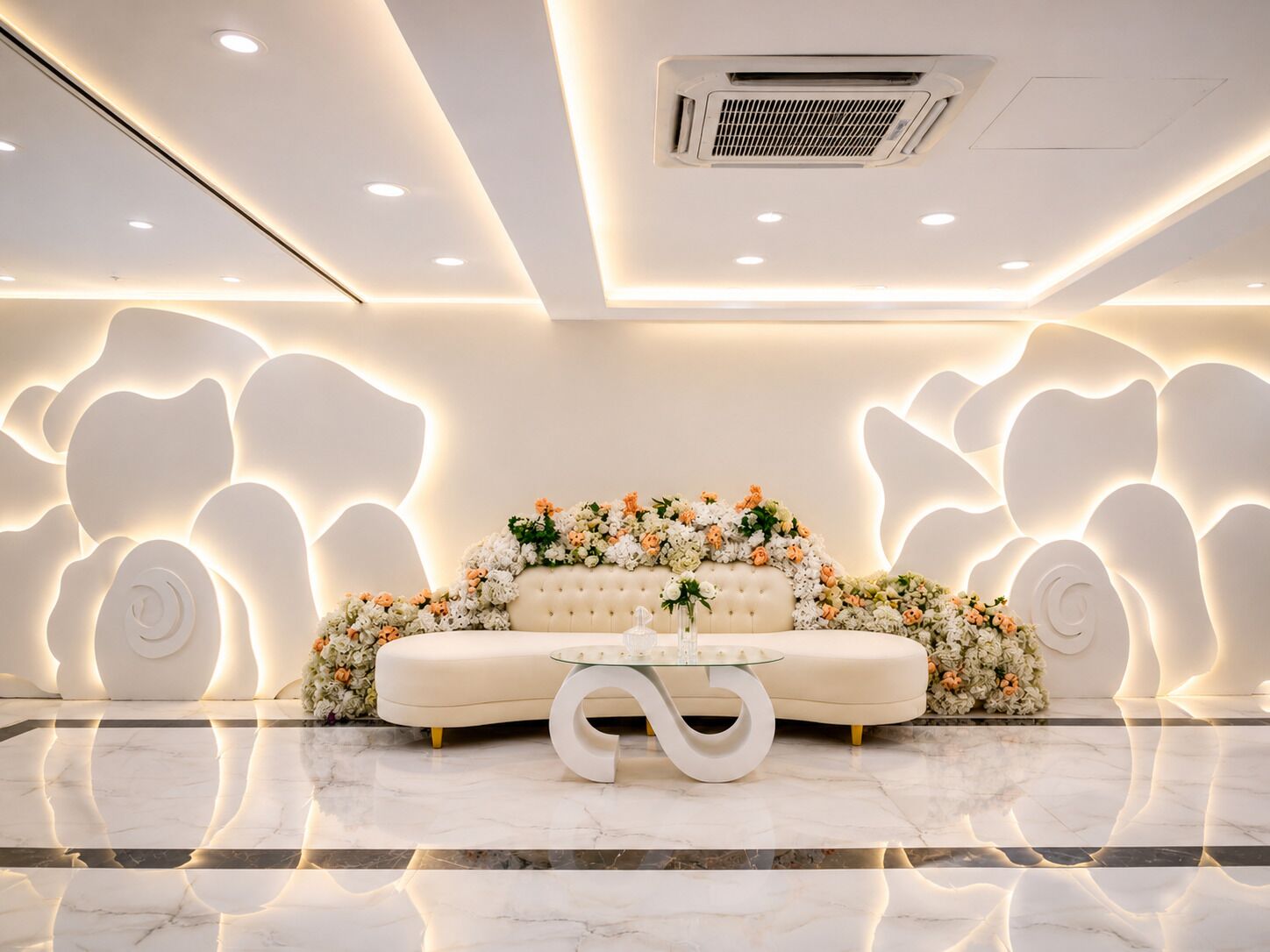 Un interior moderno con un sofá, una mesa de centro de vidrio y arreglos florales decorativos.
