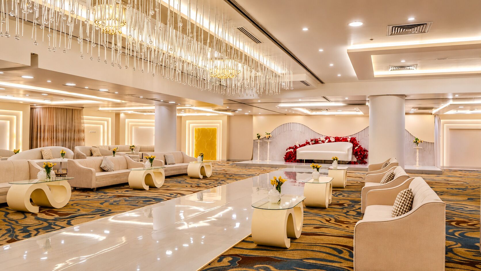 A spacious lobby with a central seating area, a reception desk, and a decorative chandelier.