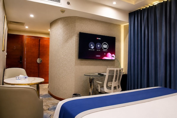 Una habitación de hotel con una cama, un escritorio, una silla, un televisor y una puerta.