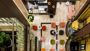 Un vestíbulo moderno con una zona de estar central, un mostrador de recepción y una escalera.