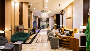 Un hall de hotel con mostrador de recepción, zona de estar y un candelabro.
