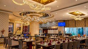 Un restaurante espacioso con varias mesas de comedor, elegantes candelabros y un fondo de pared de piedra.
