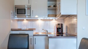Uma cozinha compacta com micro-ondas, cafeteira e pia.