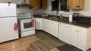Une cuisine équipée d’un réfrigérateur, d’une cuisinière, d’un four à micro-ondes et de meubles de rangement en bois.