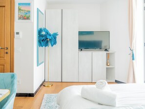 Ein Schlafzimmer mit einem Bett, einem Fernseher, einem Kleiderschrank und einem blauen Staubwedel.