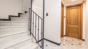 Eine Treppe mit Metallgeländer, einer Holztür und einer weißen Wand.