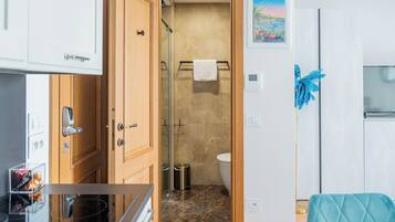 Un baño moderno con ducha de vidrio, inodoro y toalla colgada en un perchero.