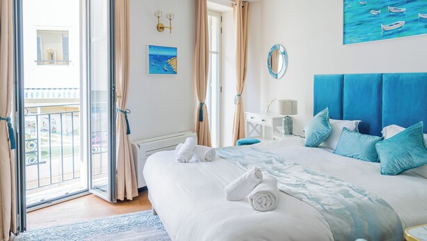 Ein Schlafzimmer mit Bett, einem Gemälde, einem Spiegel und Blick ins Freie.