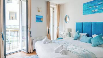Un dormitorio con cama, un cuadro, un espejo y vistas al exterior.