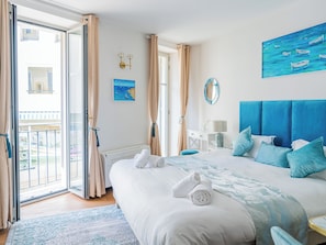 Ein Schlafzimmer mit Bett, einem Gemälde, einem Spiegel und Blick ins Freie.