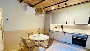 Una cuina moderna amb armaris blancs, forn integrat i zona menjador amb taula rodona i quatre cadires.